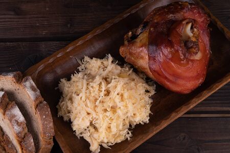Pork knuckle with sauerkraut on a wooden plate. Oktoberfest. rusticの写真素材