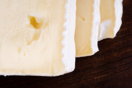Sliced smelly camembert cheese on a wooden rustic table.
