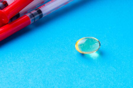 1ml insulin syringes and omega3 pills on a blue background.の写真素材