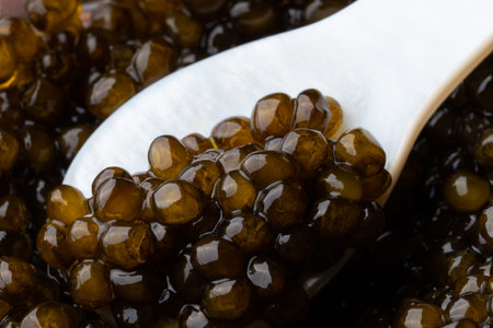Black sturgeon caviar in ceramic spoon. macro.