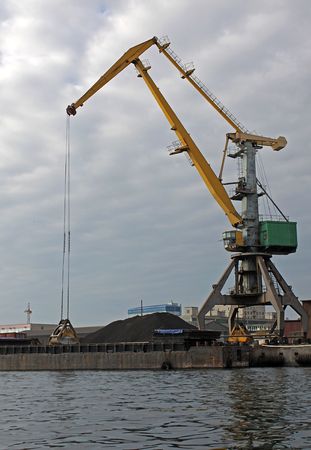 cargo crane standing near a heap of coalの写真素材