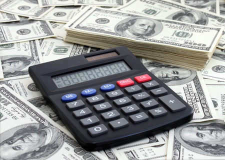 calculating income: calculator near a pile of dollarsの写真素材
