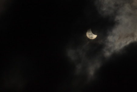 view on partial solar eclipse behind cloudsの写真素材