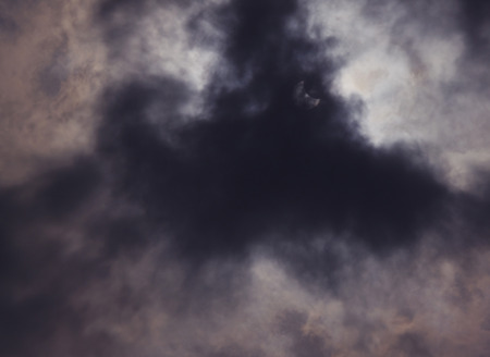 view on partial solar eclipse behind cloudsの写真素材