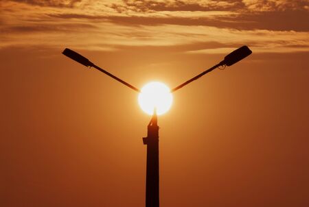 rising sun behind street lanternの写真素材