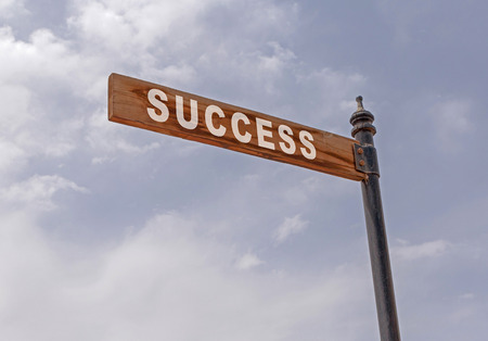 success pointer on pole against cloudy skyの写真素材