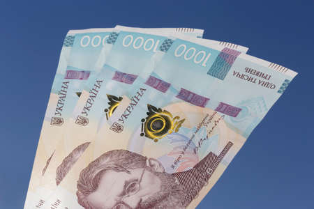 currency of Ukraine: several one thousand hrivnya banknotes against blue skyの写真素材