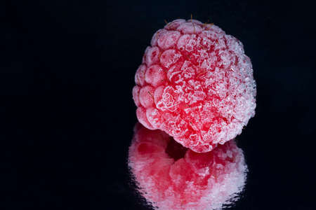 close up of frozen raspberry with reflection against black backgroundの写真素材