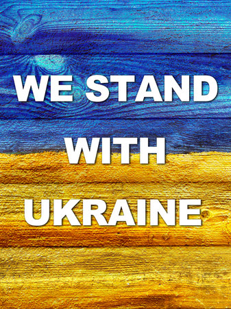 slogan We stand with Ukraine on Ukrainian flag painted on wooden wall