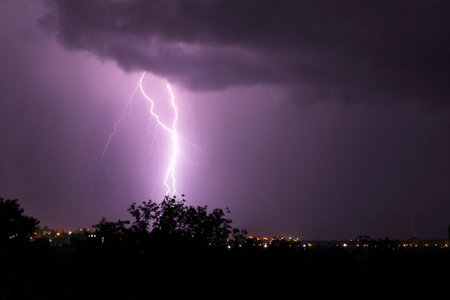 landscape with lightning striking some place in city at nightの写真素材