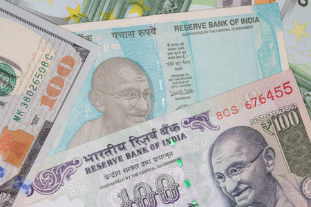 currency exchange: several Indian rupee banknotes among dollars and euro banknotes