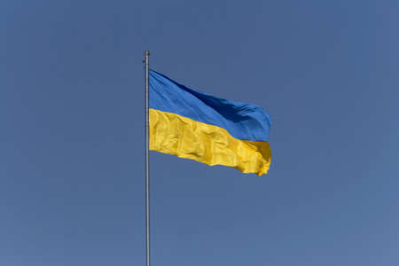 waved flag of Ukraine on flagpole against clear blue skyの写真素材