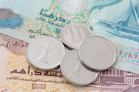 close up of United Arab Emirates dirham coins lying on banknotes