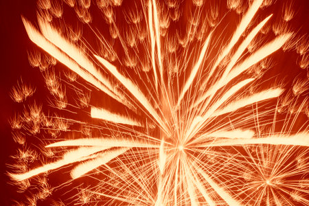 abstract holiday background: bright yellow fireworks against dark red backgroundの写真素材