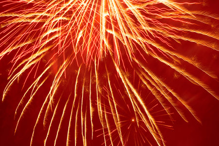 abstract holiday background: bright fireworks against dark red night skyの写真素材