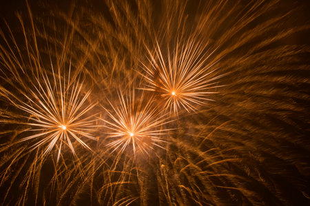 abstract holiday background: orange fireworks in night skyの写真素材