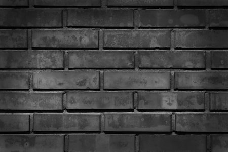 black and white photo of dark brick wall with illuminated centerの写真素材