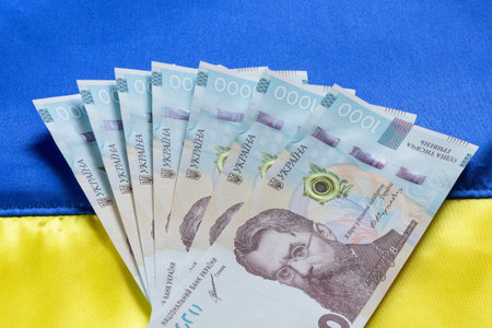 several one thousand Ukrainian hrivnya banknotes lying on fabric Ukrainian flag
