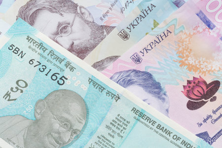 close up of fifty Indian rupee banknote lying on Ukrainian hrivnya banknotes