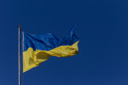 flag of Ukraine waved on flagpole against clear blue skyの写真素材