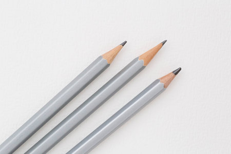 closeup of three crayon pencils laying on white sheet of paperの写真素材