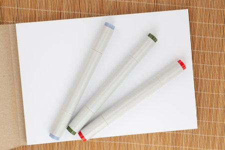 close up of opened sketch book with three markers laying on bamboo matの写真素材