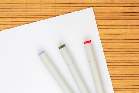 close up of three markers for sketching laying on sheet of white paperの写真素材