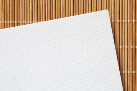 closeup of white blank sheet of paper laying on bamboo matの写真素材