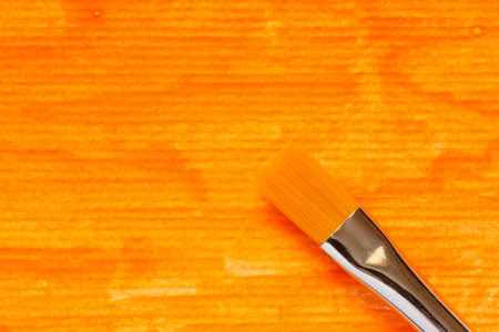 close up of paint brush at striped paper painted with orange gouacheの写真素材