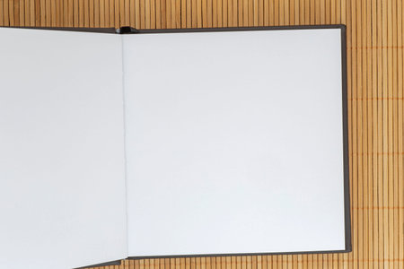 close up of  blank square page of opened sketch book lying on bamboo mat