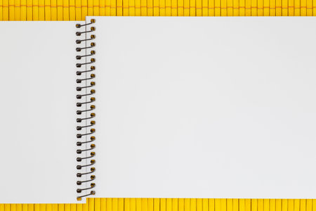 close up of blank page of sketch book laying on yellow bamboo mat
