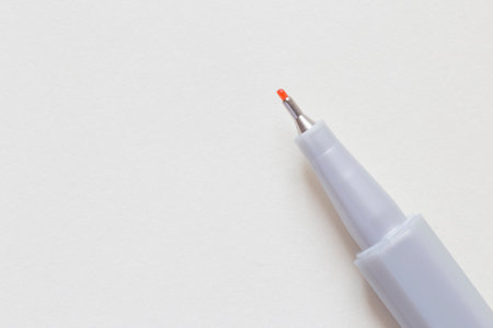 close up of tip of orange liner laying on blank page of sketch bookの写真素材