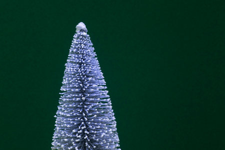 winter holiday card: white snowy Christmas tree against dark green backgroundの写真素材
