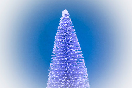 winter holiday card: snowy Christmas tree against blue backgroundの写真素材