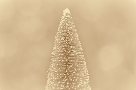 winter holiday card: snowy Christmas tree against golden bokeh backgroundの写真素材
