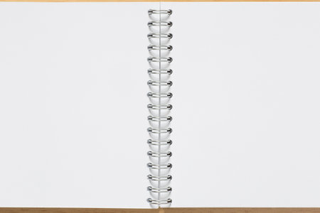 close up of blank pages of  notepad with metal binder laying on tableの写真素材