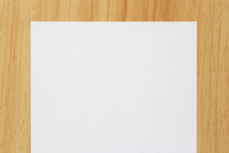 close up of blank white sheet of paper laying on wooden tableの写真素材