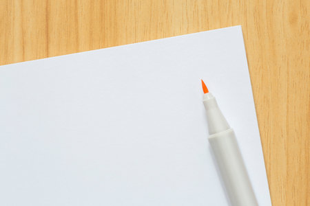 close up of marker and blank white sheet of paper laying on wooden tableの写真素材