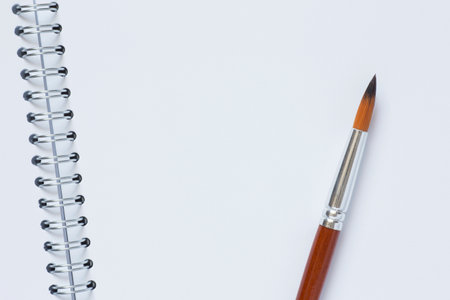 close up of paint brush laying on blank page of opened watercolor sketchbookの写真素材