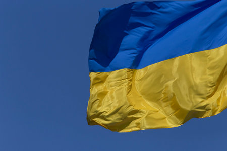 closeup of waved Ukrainian flag against clear blue skyの写真素材