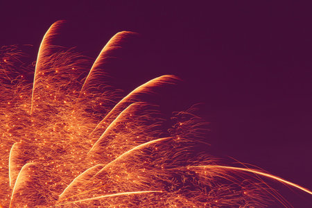 abstract holiday backdrop with blank space: yellow fireworks against dark purple night sky