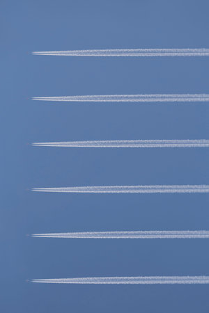 abstract travel design backdrop: six horisontal aircraft contrails against clear blue sky