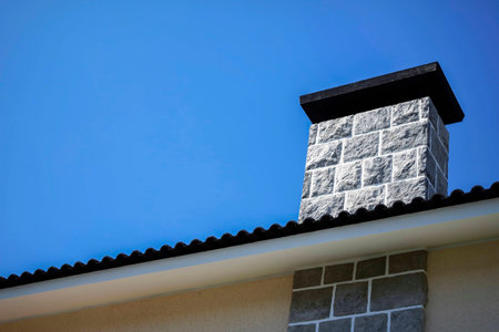 The chimney of the house rising in the blue sky background