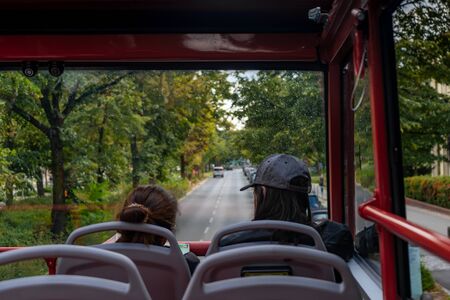 Ride the double Decker bus on the second floor on a rainy day. Ahead is an empty road and trees on the roadsides. Cloudy weather.Inside view.の写真素材