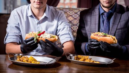 Two hungry young men eating a hot dogs in cafe. Restaurantの写真素材