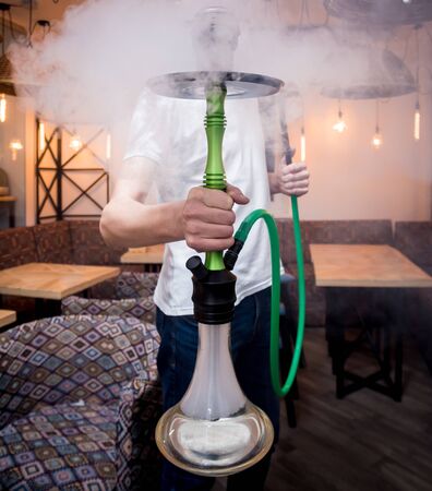 Cooking hookah in the bar. Young man with hookah in restaurant, hookah bar, smoking cafe.の写真素材