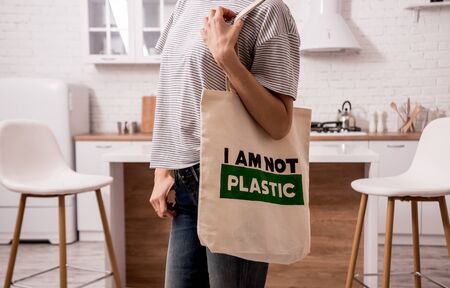 Young girl holding a cloth bag. At the kitchen. I am not plastic. Campaign to reduce the use of plastic bags. Zero wasteの写真素材