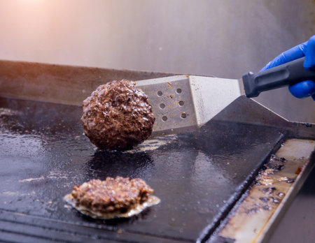 Chef preparing burgers at the kitchen grill stove. Restaurant.