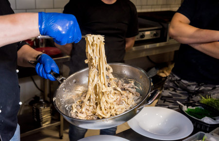 Chef cooking pasta with meat in pan. Italian style cuisine. Restaurant.の写真素材