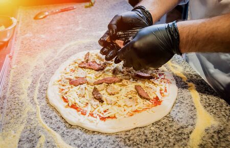 The process of making pizza. Hands of chef baker making pizza at cafe kitchenの写真素材